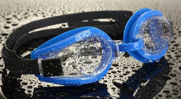 Голубые очки для плавания с капельками на сером фоне — стоковое фото