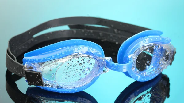 Blaue Schwimmbrille mit Tropfen auf blauem Hintergrund — Stockfoto