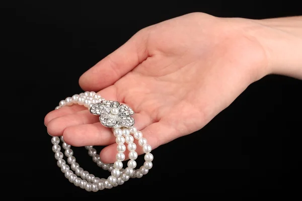 Perlenarmband in der Hand isoliert auf schwarz — Stockfoto