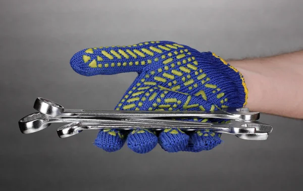 Skiftnycklar i hand med skyddet handske på grå bakgrund — Stockfoto