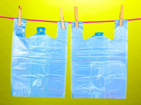 Cellophane bags hanging on rope on green background — Stock Photo, Image
