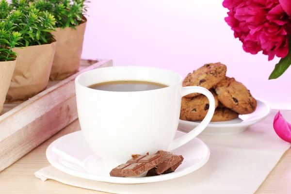 Taza de café, galletas, chocolate y flores en la mesa en la cafetería — Foto de Stock