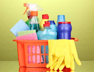 Basket with cleaning items on green background clipart