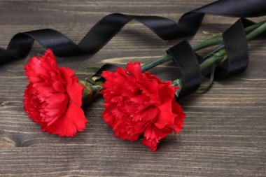 Carnations and black ribbon on grey wooden background clipart