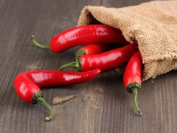 Red hot chili peppers in bag on wooden background — Stock Photo, Image