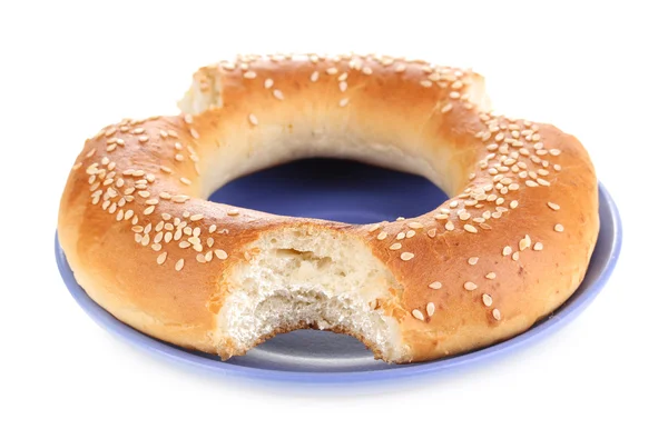 Bitten bagel with sesame seeds on plate isolated on white — Stock Photo, Image