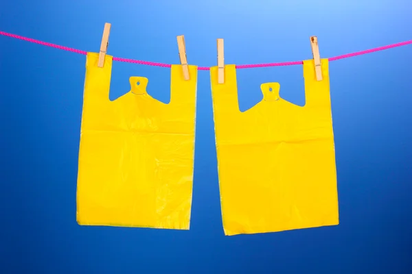 Cellophane bags hanging on rope on blue background — Stock Photo, Image