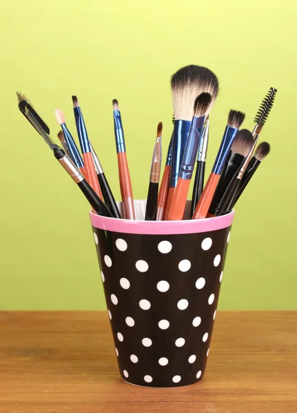 Make-up-Pinsel in einer schwarzen Tasse mit Punkten auf gelbem Hintergrund — Stockfoto