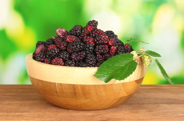밝은 녹색 백그라운드 클로즈업에 나무 테이블에 익은 mulberries 나무 그릇 — 스톡 사진