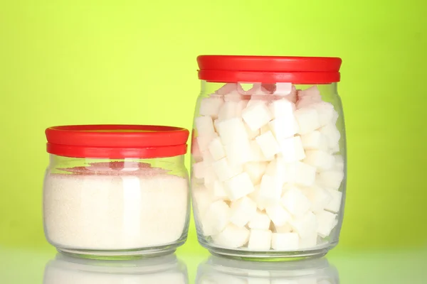 Frascos con azúcar en terrón blanco y azúcar cristalina blanca sobre fondo colorido — Foto de Stock