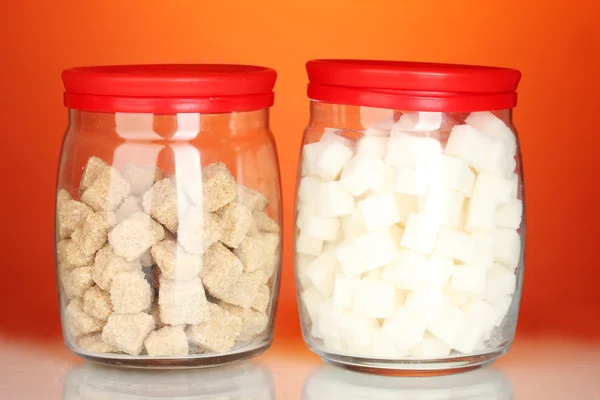 Gläser mit braunem Rohrzuckerklumpen und weißem Zuckerklumpen auf buntem Hintergrund — Stockfoto