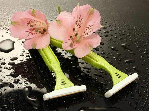 Woman safety shavers and flowers with drops on grey backgroud — Stock Photo, Image