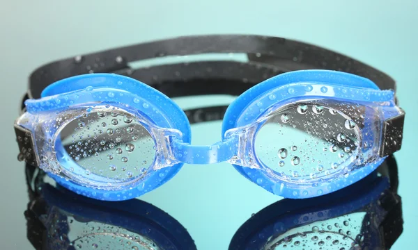 Óculos de natação azuis com gotas no fundo azul — Fotografia de Stock