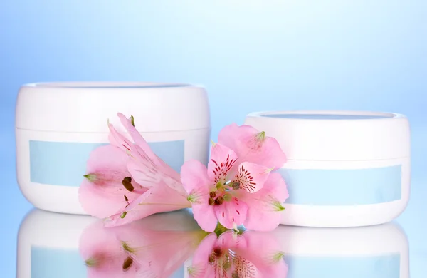 Vasi di crema con fiore su sfondo blu — Foto Stock