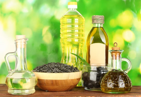 Olive and sunflower oil in the bottles and small decanters on green background close-up — Stock Photo, Image