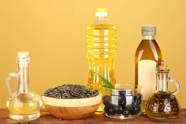 Olio di oliva e girasole nelle bottiglie e piccoli decanter su fondo giallo primo piano — Foto Stock