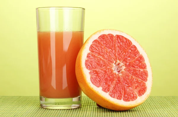 Grapefruitsaft und Grapefruit auf Bambusmatte auf grünem Hintergrund — Stockfoto