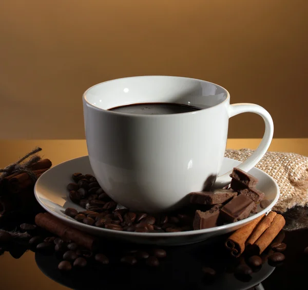 Tazza di caffè e fagioli, bastoncini di cannella e cioccolato su sfondo marrone — Foto Stock