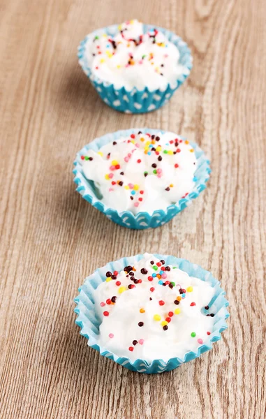 Cremige Cupcakes auf hölzernem Hintergrund — Stockfoto