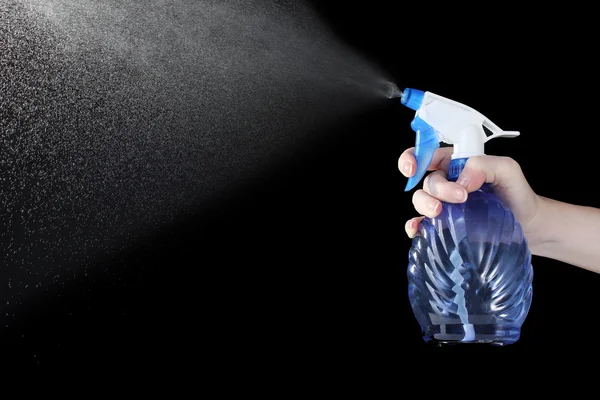 Hand hålla sprayflaska och spraya på svart bakgrund — Stockfoto