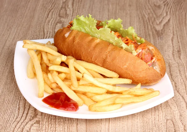 stock image Appetizing hot dog with fried potatoes on plate on wooden table