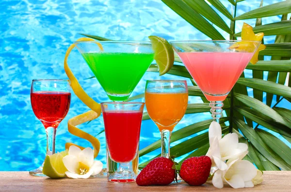 Exotic cocktails and flowers on table on blue sea background