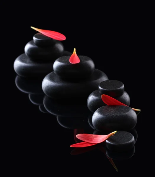 Wellness-Steine und Blütenblätter auf schwarzem Hintergrund — Stockfoto