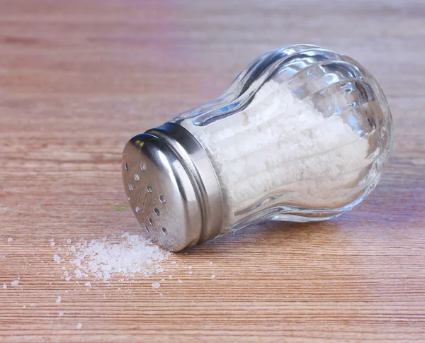 Saleiro de vidro com sal sobre fundo de madeira — Fotografia de Stock