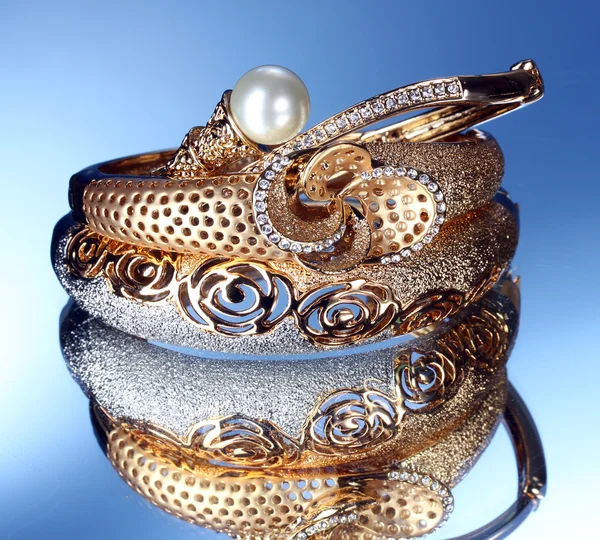 Beaux bracelets en or sur fond bleu — Photo