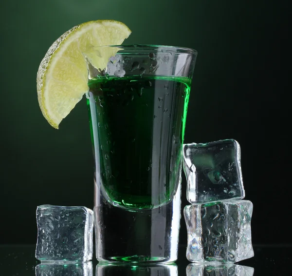 Glass of absinthe, lime and ice on green background — Stock Photo, Image