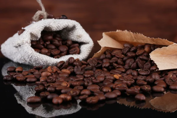 Kávová zrna v plátno pytle a papíru taškou izolovaných na dřevěné — Stock fotografie