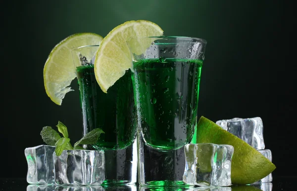 Two glasses of absinthe, lime and ice on green background — Stock Photo, Image