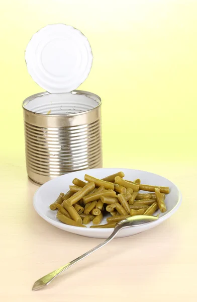 打开锡罐和板与法国豆和绿色背景上的木桌上的勺子 — 图库照片