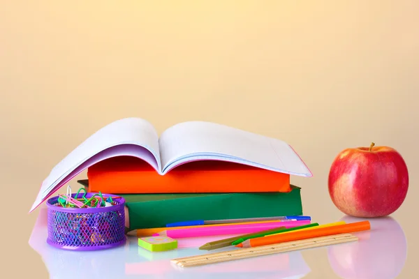 Sammansättningen av böcker, pappersvaror och ett äpple på färgstarka bakgrund — Stockfoto