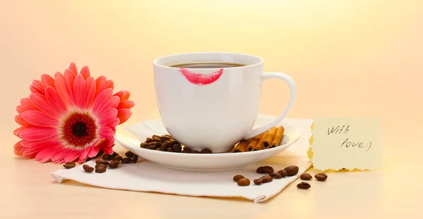 Taza de café con marca de lápiz labial y granos de gerberas, palitos de canela en la mesa de madera — Foto de Stock