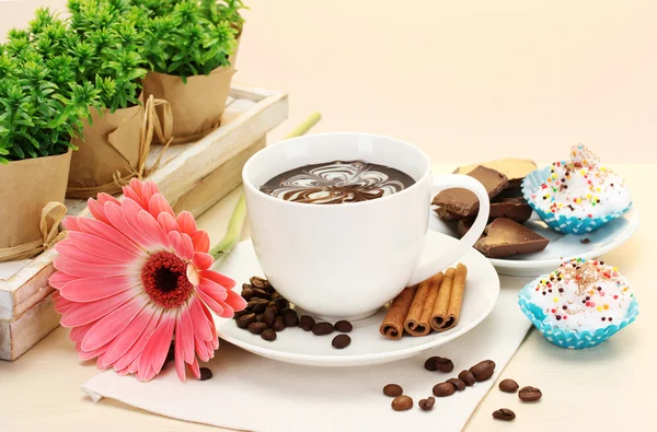 Kopje koffie en gerbera bonen, kaneel stokken op houten tafel — Stockfoto