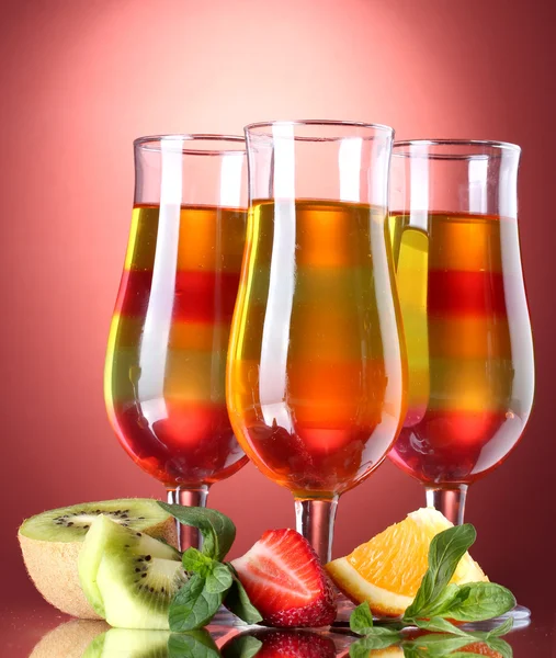 Fruit jelly in glasses and fruits on red background — Stock Photo, Image