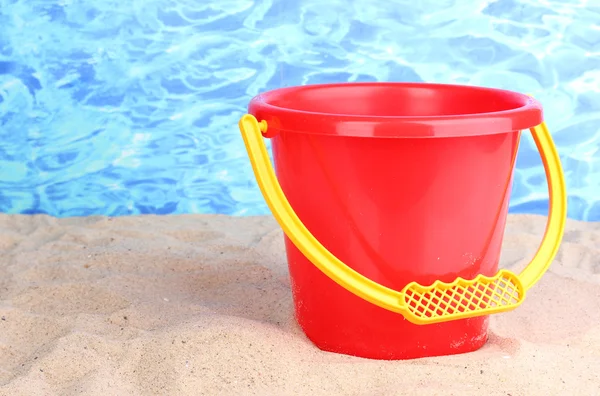 Children's bucket on sand on water background — Stock Photo, Image