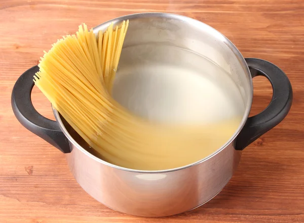 Gotować spagetti na patelni na drewniane tło zbliżenie — Zdjęcie stockowe