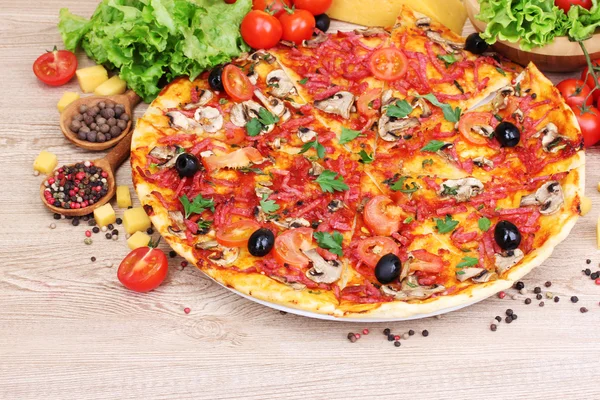 Смачна піца та овочі на дерев'яному столі — стокове фото