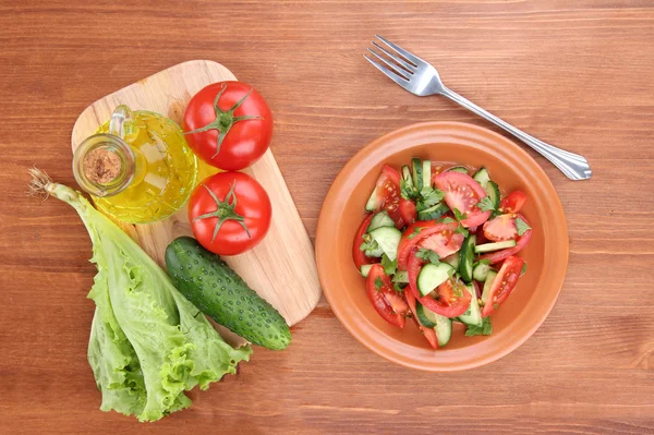 Свіжий салат з помідорами та огірками на дерев'яному фоні — стокове фото