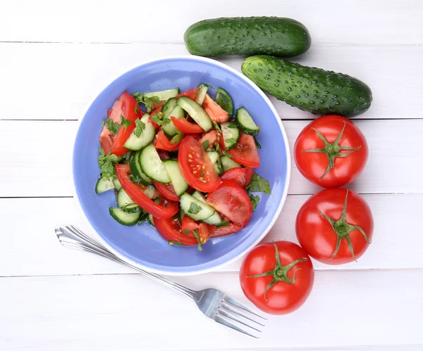 Fresh salad with tomatoes and cucumbers on white wooden background — Stock Photo, Image