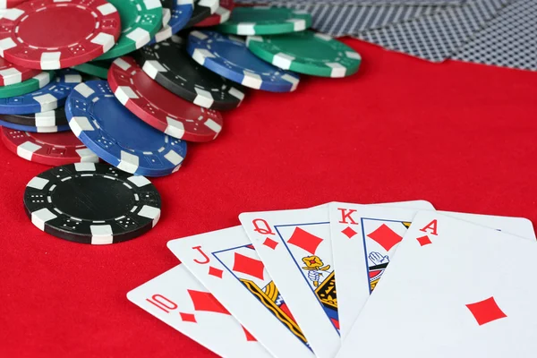 Escalera real con fichas de póquer en un primer plano de mesa de póquer rojo —  Fotos de Stock