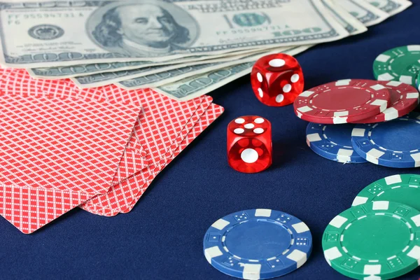 Игральные карты и фишки для покера с костями и долларами на синем покерном столе крупным планом — стоковое фото