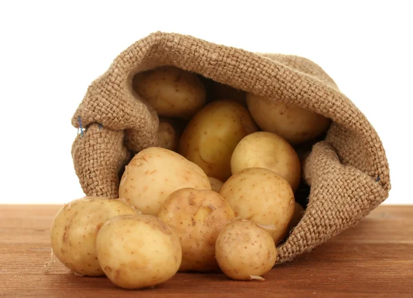Młode ziemniaki w worek na stole na białe tło zbliżenie — Zdjęcie stockowe