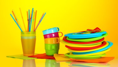 Bright plastic disposable tableware on colorful background clipart