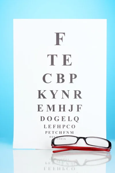 Tabla de pruebas de la vista con gafas en primer plano de fondo azul — Foto de Stock