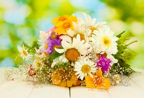 Beautiful bouquet of bright wildflowers, on wooden table on green background — Stock Photo, Image
