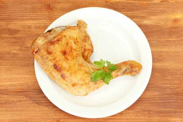 Cuisse de poulet rôti avec du persil dans l'assiette sur fond en bois close-up — Photo