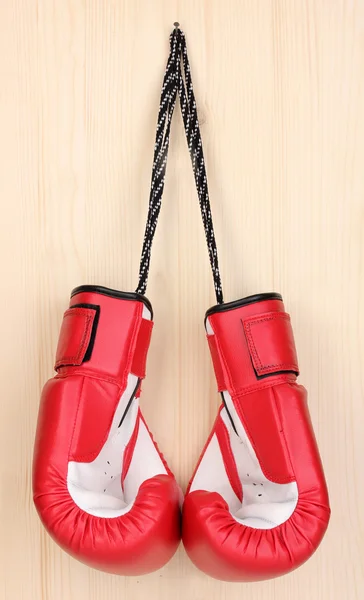 Červené Boxerské rukavice zavěšené na dřevěné pozadí — Stock fotografie